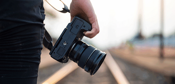 Pressefotograf mit professioneller Kamera an Bahngleisen