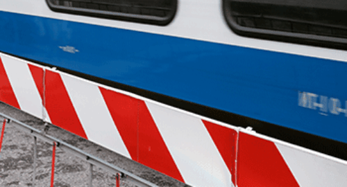 Red and white barrier gate in front of the blue exterior wall of a train from Bentheimer Eisenbahn AG