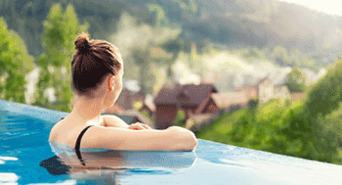 Entspannung in einem Infinity-Pool mit Blick auf grüne Natur und Hügellandschaft