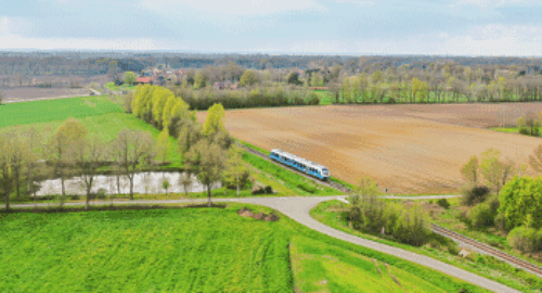 Luftaufnahme einer idyllischen Zugstrecke durch grüne Felder, Wälder und ländliches Gebiet