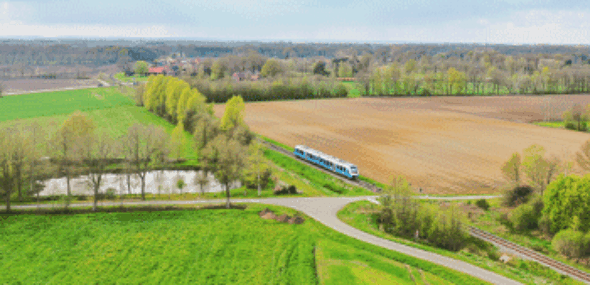 Luftaufnahme einer idyllischen Zugstrecke durch grüne Felder, Wälder und ländliches Gebiet