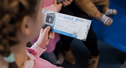 Kind hält ein personalisiertes Ticket der Bentheimer Eisenbahn AG in den Händen