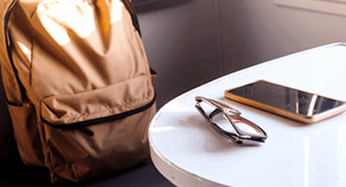 Liegengeblassener Rucksack, Sonnenbrille und Smartphone auf einem Tisch im Zug