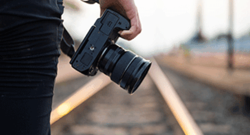 Pressefotograf mit professioneller Kamera an Bahngleisen